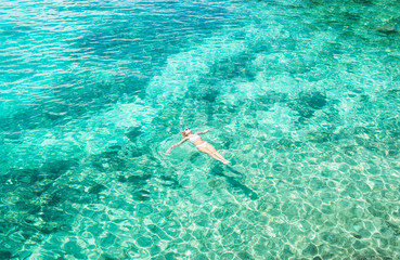 Wall Mural - Young woman swimming in the beautiful blue sea. Overhead view. Aerial shot.