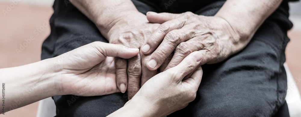 Caregiver, carer hand holding elder hand in hospice care background. Philanthropy kindness to disabled old people concept.Happy mother's day. - obrazy, fototapety, plakaty 