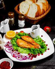 Canvas Print - fried salmon fillets served with red onion rings lettuce lemon and pomegranate sauce