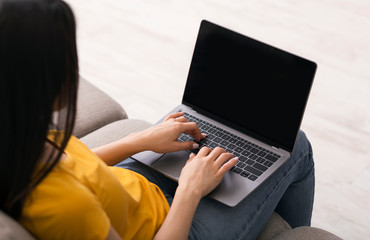 Wall Mural - Working or studying online. Young girl using laptop with blank screen at home, space for your design