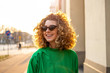 © pikselstock - Portrait of young woman with curly hair in the city