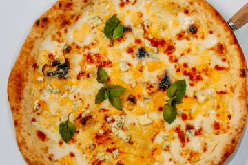 Italian pizza with different types of cheese and basil on a white background