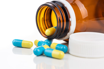 Close-up of medicine in capsule format with bottle on white background