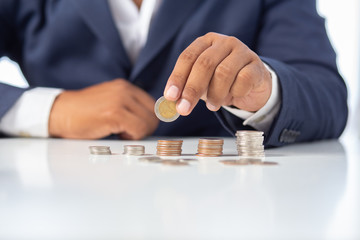 Businessman hand with putting money coins a desk in the office.concept: Saving money wealth and financial Personal, finance management  loan for a home, diagram chart earnings to plan profit