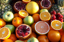 Heap Of Orange, Pomegranate, Apples And Other Fruits Whole And Sliced As Background      