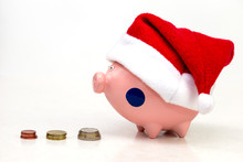 Close-up Of Coins By Piggy Bank With Santa Hat Over White Background