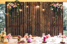 Wedding Venue. Wooden Wall At The Banquet Table With Lamps And Flowers. Copy Space