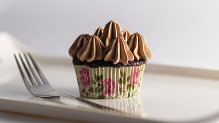 Wall Mural - Cupcake with Chocolate Icing with a fork and a White background