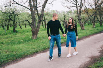 couple in blue jeans and black shirts in a green park