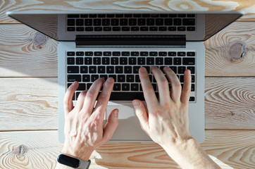 Fototapete - Top view of man's hands typing on laptop in sunny day. Coworking or working at home concept image.
