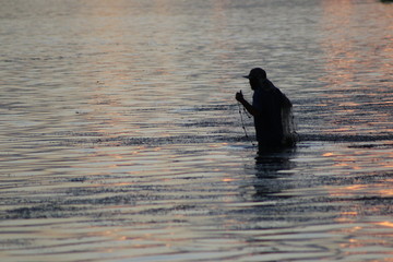 Wall Mural - a man fishing with a cast net