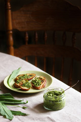 Canvas Print - Pesto from wild garlic and fried toast from baguette on the table. Back of chair in the background. life style food