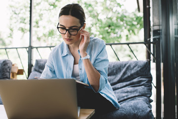 Pensive adult woman working on laptop while sitting at table on terrace