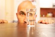 Male staring at a glass filled with alcohol - alcohol addiction concept