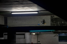 Security Camera On Illuminated Ceiling At Underground Parking Lot