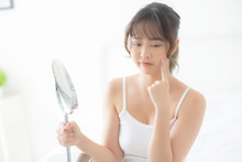 Beautiful Young Asian Woman Looking The Mirror With Acne Problem At Bedroom, Trouble Of Beauty On Face, Zit Treatment, Asia Girl Is Pimple Having Worry And Displeased, Skincare And Healthy Concept.