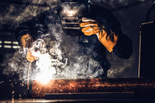 Metal Welder Working With Arc Welding Machine To Weld Steel At Factory While Wearing Safety Equipment. Metalwork Manufacturing And Construction Maintenance Service By Manual Skill Labor Concept.