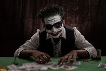 Portrait Of An Indian Man In Halloween Costume Showing Scary Facial Expression In Front Of A Casino Poker Table. Cosplay Photography.