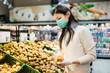 © eldarnurkovic - Woman with mask safely shopping for groceries amid the coronavirus pandemic in a stocked grocery store.COVID-19 food buying in supermarket.Panic buying,stockpiling.Shortage of fresh produce,vegetables