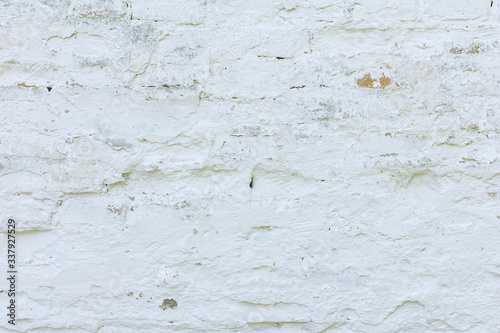 The brick wall is whitewashed, cracked old.