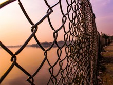 Close-up Of Chainlink Fence Against Sky During Sunset