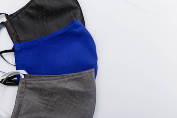 Close-up of three handmade medical masks of different colors, black, blue and gray isolated on a white background. The concept of scarcity of medical masks and the popularization of handmade masks.