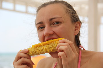 Girl eating corn on the beach in summer