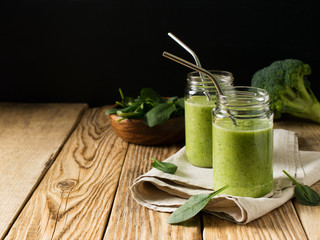 Green smoothie in glass jar with straw and spinach and broccoli