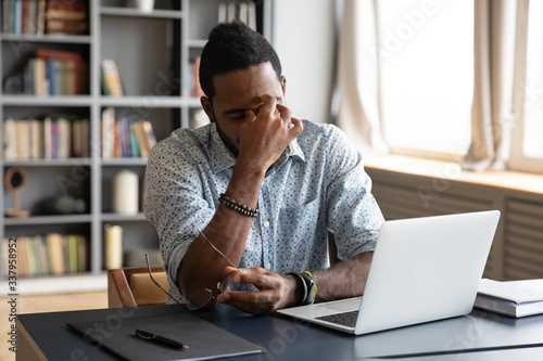 Cuadros en Lienzo Frustrated young biracial guy taking off eyeglasses, massaging nose bridge, feeling tired due to computer overwork