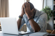 © fizkes - Head shot desperate millennial mixed race man holding head in hands, feeling exhausted after long computer work. Tired frustrated young biracial businessman suffering from financial problems.