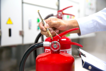 Fireman are checking and inspection red tank of fire extinguisher.Concepts of Emergency and safety equipment for fire prevention and training on the use of fire extinguishers.