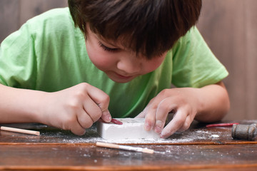 Children having fun with archaeology excavation kit. Boy plays an archaeologist excavated, training for dig fossil