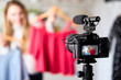 © artiemedvedev - Fashion blogger woman in jeans and turtleneck showing casual colorful shirts on camera. Stylist influencer girl showing trendy clothes filming vlog episode for her channel. Opinion leader sets trends.