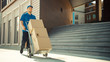 © Gorodenkoff - Happy Young Delivery Man Pushes Hand Truck Trolley Full of Cardboard Boxes and Packages For Delivery. Professional Courier Working Efficiently and Quickly. In the Background Stylish Modern Urban Area