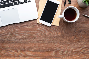 Wall Mural - Wood office desk table with smartphone with blank screen, laptop computer, cup of coffee and supplies. Top view with copy space, flat lay.