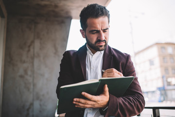 Wall Mural - Serious businessman writing in planner on balcony