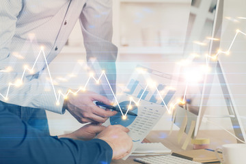 Double exposure of chart with businessman typing on computer in office on background. Concept of hard work.