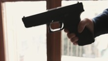 Adult Offering A Nine Millimeter Gun To A Young Boy At Home Close Up