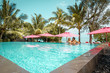 Paar entspannt am Pool umgeben von Palmen mit Meerblick auf Mauritius