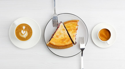 Two pieces of homemade raspberry pie and two cups of coffee esptesso and cappuccino on white wooden table. Top view.