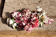 Faded Plastic Flowers Lying On A Grave