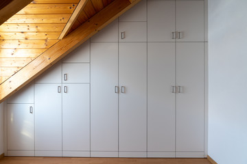 interior view of a custom-made closet built into a master bedroom with a sloping roof