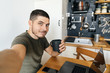 © galaganov - Handsome man taking selfie while working on laptop at home in modern loft kitchen. Remote work.