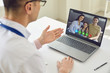 © Studio Romantic - Family doctor online. Male doctor speaks with patients by family using laptop sitting behind straw in clinic office.