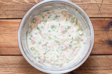 Step-by-step preparation of a pie with sausage, cheese and green onions, step 4 - mixing the dough with the filling, selective focus