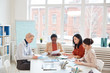 © Seventyfour - Diverse group of successful businesswomen discussing project while sitting at table against window during meeting in conference room, copy space