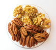Pecans and walnuts in a glass plate on a light background
