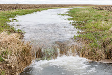Motion Blur Of Water Flowing In Farm Field Waterway To Ditch After Heavy Rain And Storms Caused Flooding. Concept Of Soil Erosion And Water Runoff Control And Management