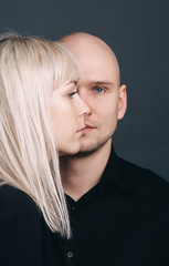 Woman and man posing on dark blue background, aligning their faces side to front