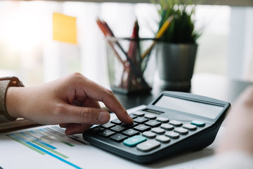 Close up hand of  accountant or banker working on calculator to calculate financial data report, accountancy document, business work at home concept